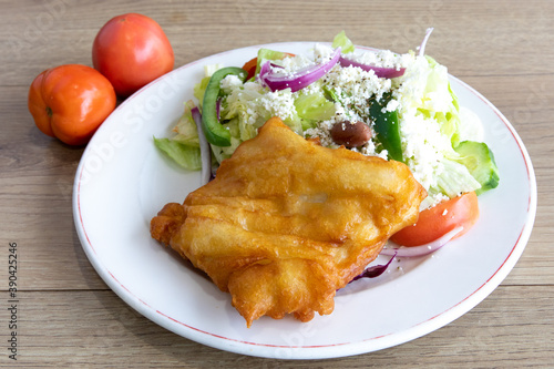 Battered halibut fish and salad on a white plate