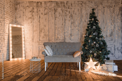 new year's interior in a classic style with a gray sofa, a Christmas tree and a mirror with light bulbs and garlands