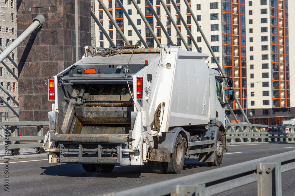 Fototapeta premium Garbage truck driving on the highway in the city, back view.