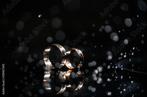 gold wedding rings for newlyweds on a wedding day on a black background with water drops. Jewelry © Дмитрий Ткачук