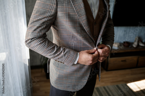 Stylish man groom buttoning a button on his jacket