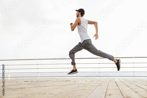 Focused unshaven guy running while working out