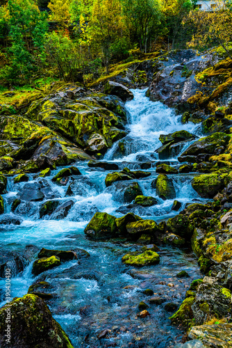 Beautiful waterfall flowing through a forest in lush autumn colors of green and yellow shades.