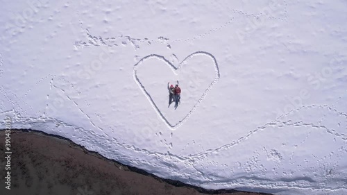 Couple Valentine's day,  heart on snow by the lake. Aerial zoom out photo