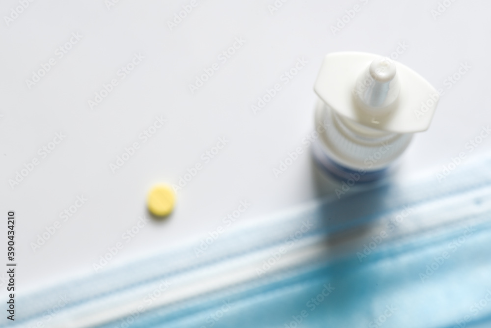 Surgery face mask with yellow pill tablets and Nasal Spray on white background