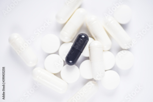 Carbon capsules suround by white medicine on white background