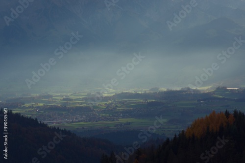 Small green hills in valley lit by sunbeams shinig through the mist