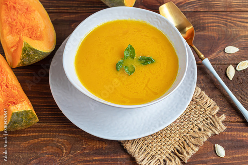 Fresh pumpkin cream soup with sour cream. Autumn lunch concept. On a wooden background. A dietary, healthy dish.