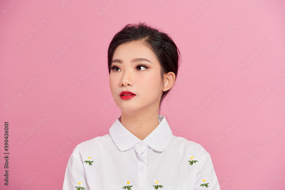 Cute and attractive asian woman standing in modest smiling at camera while standing over pink background. Cute and attractive asian woman standing in modest smiling at camera while standing over pink background.