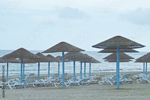 Tumbonas y sombrillas de paja en la playa Olimp en Rumania. Playa vac  a un nublado y fr  o d  a de verano.