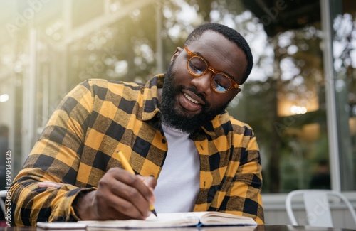 Fotografija Happy African American business man writing on notebook, working project