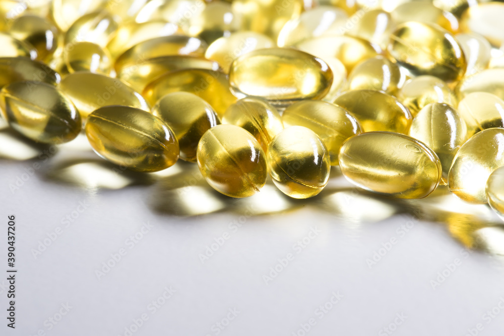 Golden, shiny oil capsules on a white background. CBD oil or cod liver oil Golden, shiny oil capsules on a white background. CBD oil or cod liver oil