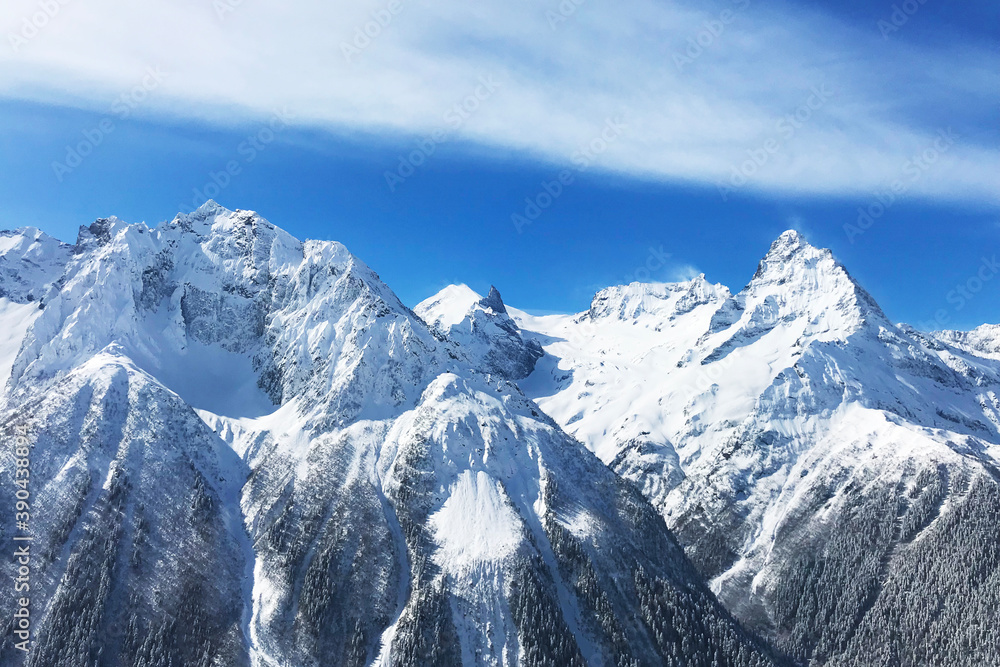 snowy peaks of high mountains and blue sky with clouds. Extreme adventures in mountains