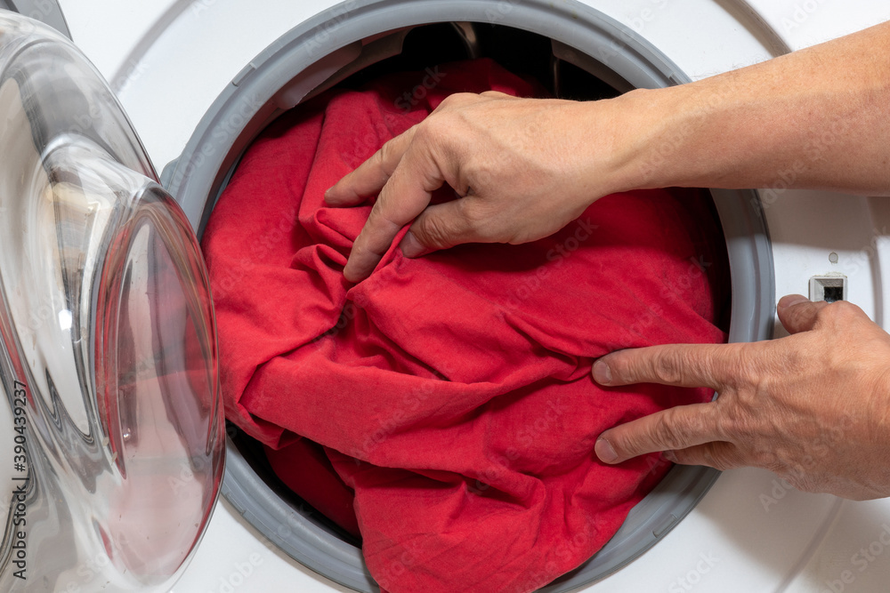 Loading bed linen into a household washing machine. Loading bed linen into a household washing machine.
