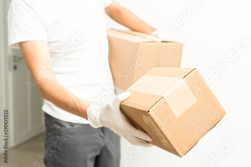 Delivery man holding cardboard boxes in medical rubber gloves and mask. copy space. Fast and free Delivery transport . Online shopping and Express delivery . Quarantine © Angelov