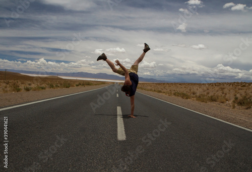 B boy. Young caucasian man handstand in the asphalt desert road. 