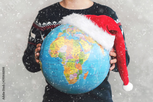 Merry Christmas. kid holding earth globe with a Santa hat