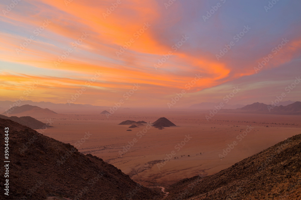 Orange wind swept clouds after sunset in the Namib Desert