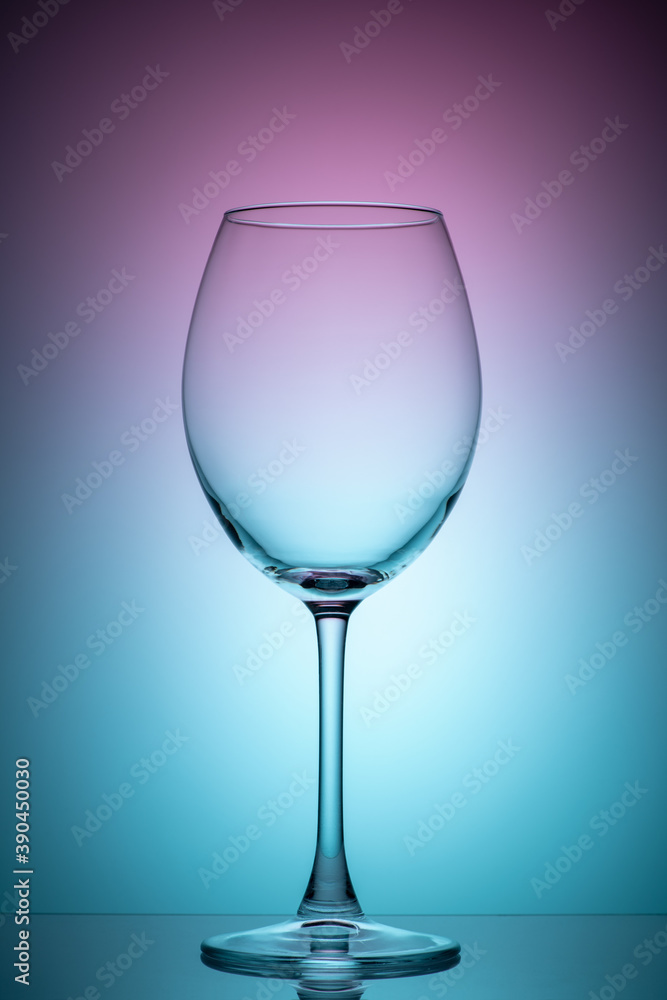 The wine glass is empty with purple and blue color filters. Photo of glass on the lumen with filters. Vertical photo
