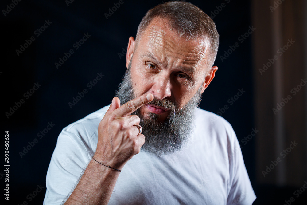 Emotional portrait of an adult gray-haired man with a beard in a white t-shirt Emotional portrait of an adult gray-haired man with a beard in a white t-shirt