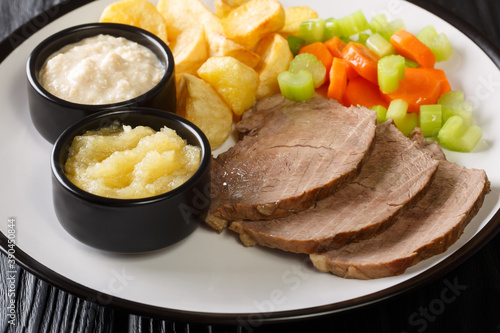Photography classic Austrian main dish Tafelspitz is beef simmered until tender then served with a variety of vegetables and horseradish sauce close-up in a plate on the table