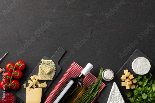 Composition with wine bottle and cheese assortment on grey background