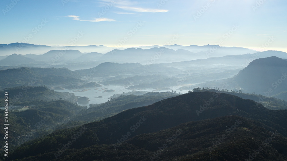 Fresh mountains landscape on sunrise with clear sky. Panoramic view from Adam's Peak (Sri Pada) with soft blue color gradients. Valley with Maskeliya reservoir. Freshness and tranquility. Sri Lanka