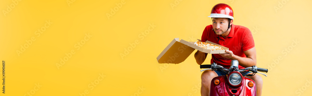 delivery man in helmet riding scooter and holding pizza in box on yellow, banner delivery man in helmet riding scooter and holding pizza in box on yellow, banner
