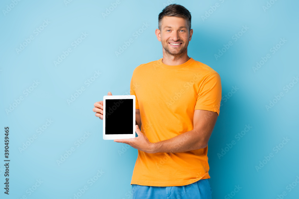 happy man in t-shirt holding digital tablet with blank screen on blue happy man in t-shirt holding digital tablet with blank screen on blue