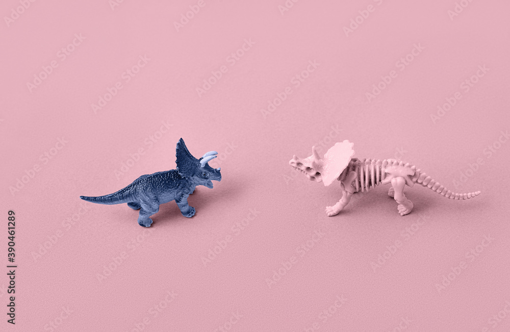 Fototapeta premium Toy models of dinosaur skeletons on a pink background.