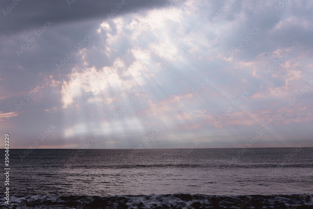Sun rays shining from the sky to the black calm sea Sun rays shining from the sky to the black calm sea