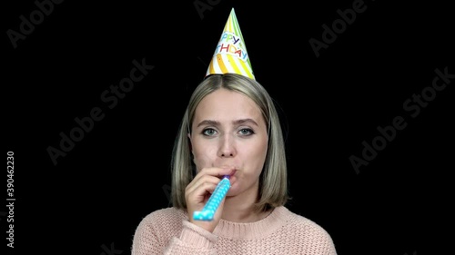 Woman in party hat happy birthday blowing party horn on black backgroundbirthday photo