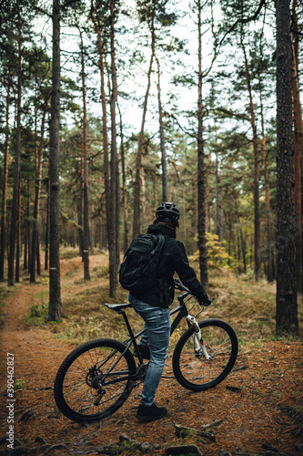 Young man mountainbiker with bicycle along a forest trail, MTB bike ride