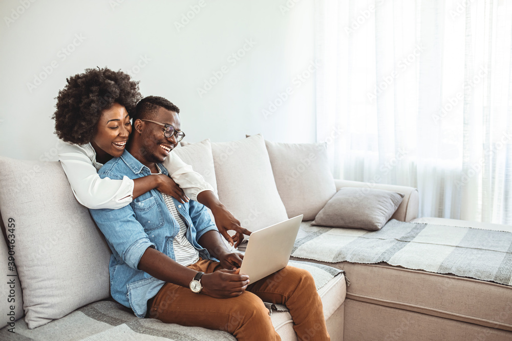 Cheerful couple relaxing together on couch surfing internet on laptop at home. Young couple at home enjoy in weekend, they are using laptop while resting.