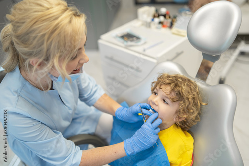 Cute young boy visiting dentist  having his teeth checked by female dentist in dental office.