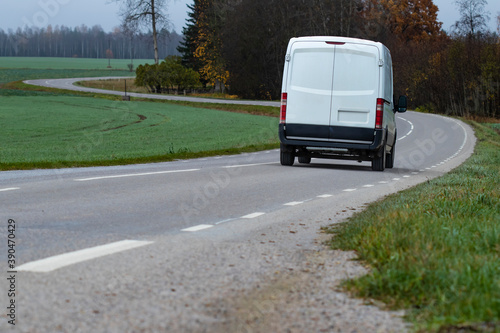 A fictional cargo delivery van driving on a curvy countryside road 