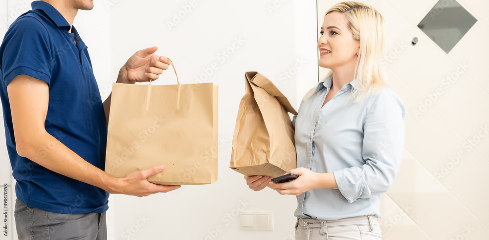 woman receiving boxes from postman at the door in home delivery concept. Woman received the parcel from the postman at home. Postman giving cardboard box to young woman. woman receiving boxes from postman at the door in home delivery concept. Woman received the parcel from the postman at home. Postman giving cardboard box to young woman.
