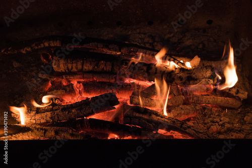 Fire in a fireplace from conflagrant wooden logs. Burning logs in a small campfire.