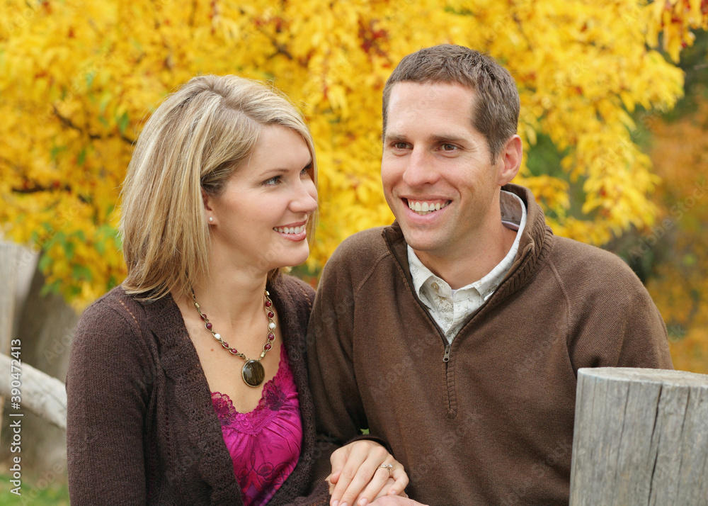 Fototapeta premium attractive couple standing together outdoors against yellow tree background
