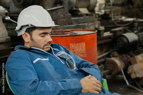 Young engineer, labor or worker man with white halmet  take a nap because so tired after hard work. Sleeping during work, sleep at workplace, Over time employee. Copy Space.