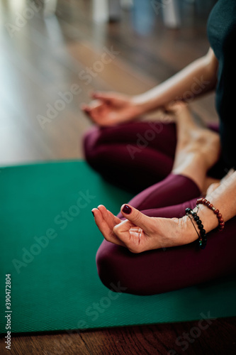 Closeup of woman sitting in lotus position and meditating at home.