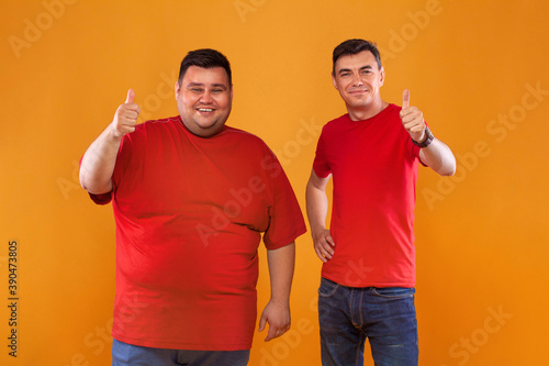 Fat and thin guys in red t-shirt. Two men with different complexion isolated on a yellow background. Ectomorph and endomorph photo