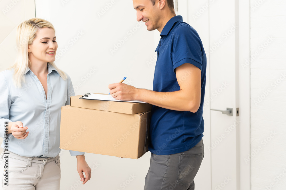 woman receiving boxes from postman at the door in home delivery concept. Woman received the parcel from the postman at home. Postman giving cardboard box to young woman. woman receiving boxes from postman at the door in home delivery concept. Woman received the parcel from the postman at home. Postman giving cardboard box to young woman.