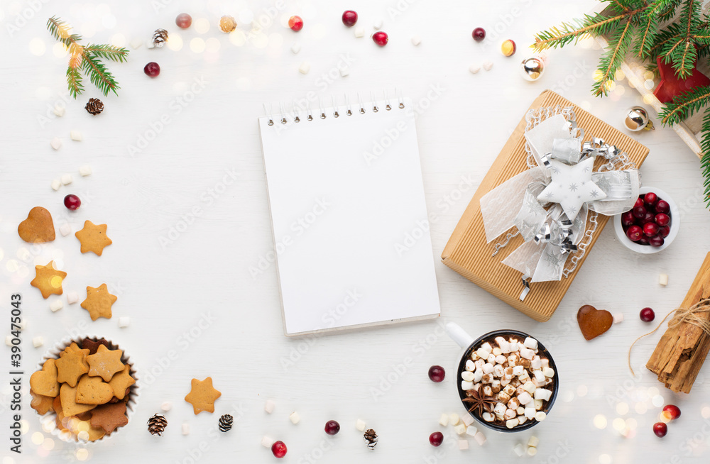 Obraz premium Christmas gift box, empty notebook, cup of hot chocolate drink and homemade gingerbread cookies on white wooden background.