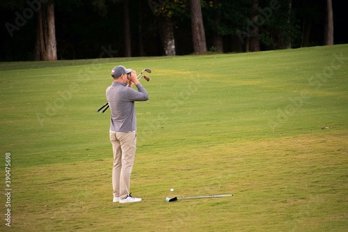 A man golfer scoping and studying and calculating his next shot on the fairway to the golf green on a hard and difficult luxury country club golf course. 
