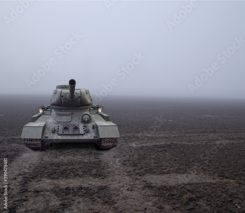 A tank approaching from fog on a muddy field on tracks photo