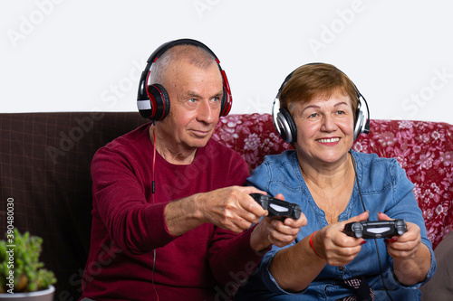 A senior couple are playing in a game room at home with headphones and having fun.