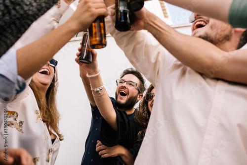 portrait of a group of friends toasting and celebrating. Everyone smiles and holds a beer each