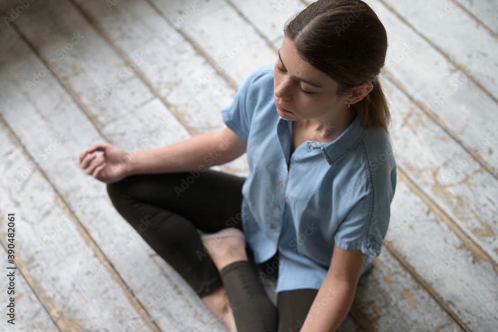 Young woman meditating sitting on the floor in an empty construction apartment