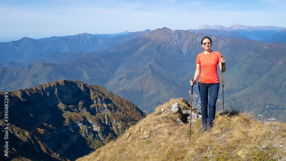 Woman hiker goes hiking, stands on top of mountain and looks at autumn nature mountains landscape in sunny weather. Outdoor activities. Copy space Woman hiker goes hiking, stands on top of mountain and looks at autumn nature mountains landscape in sunny weather. Outdoor activities. Copy space